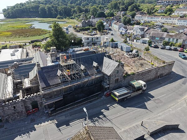 Island House from the north, its roofs under repair, with the terraces of Laugharne and the estuary behind.