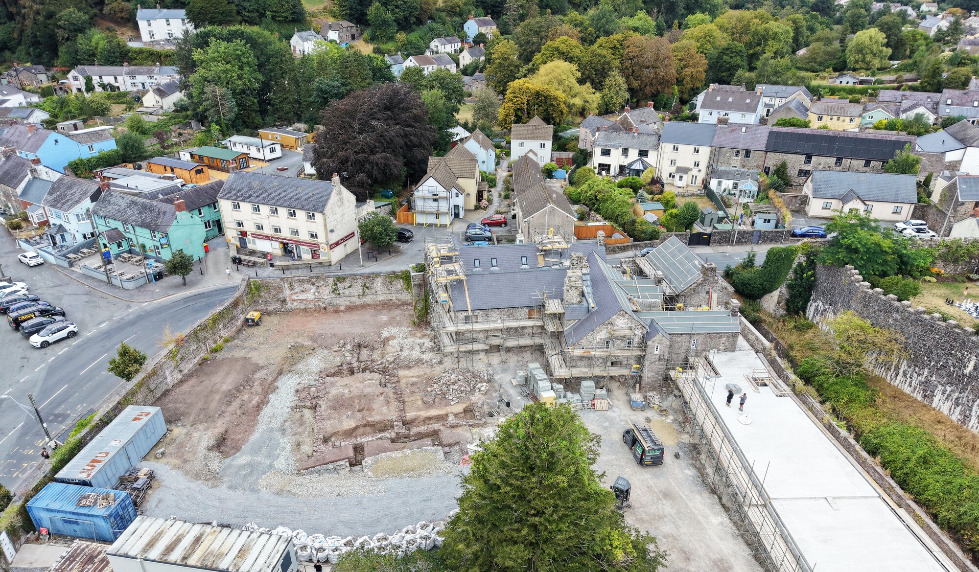 Aerial view of the excavated medieval foundations in the yard beside Island House, with the house under restoration behind and the town of Laugharne beyond.