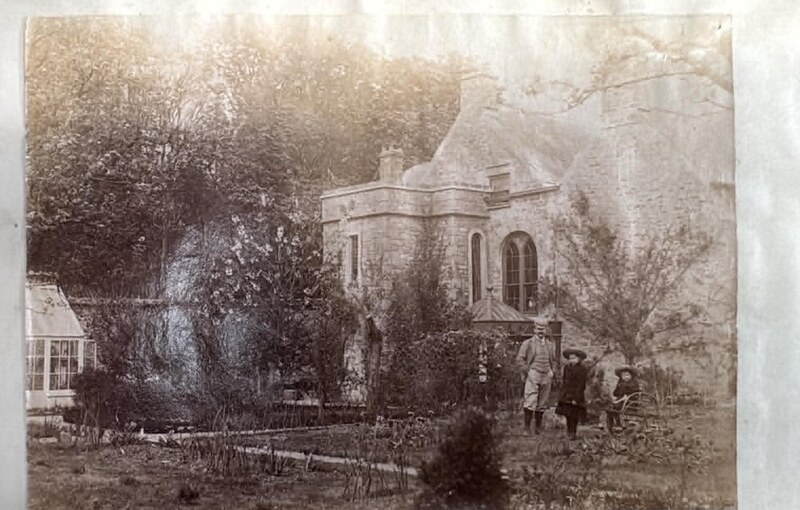 A Victorian photograph of the household standing in the garden of Island House, the ivy-grown house and its arched windows behind them.